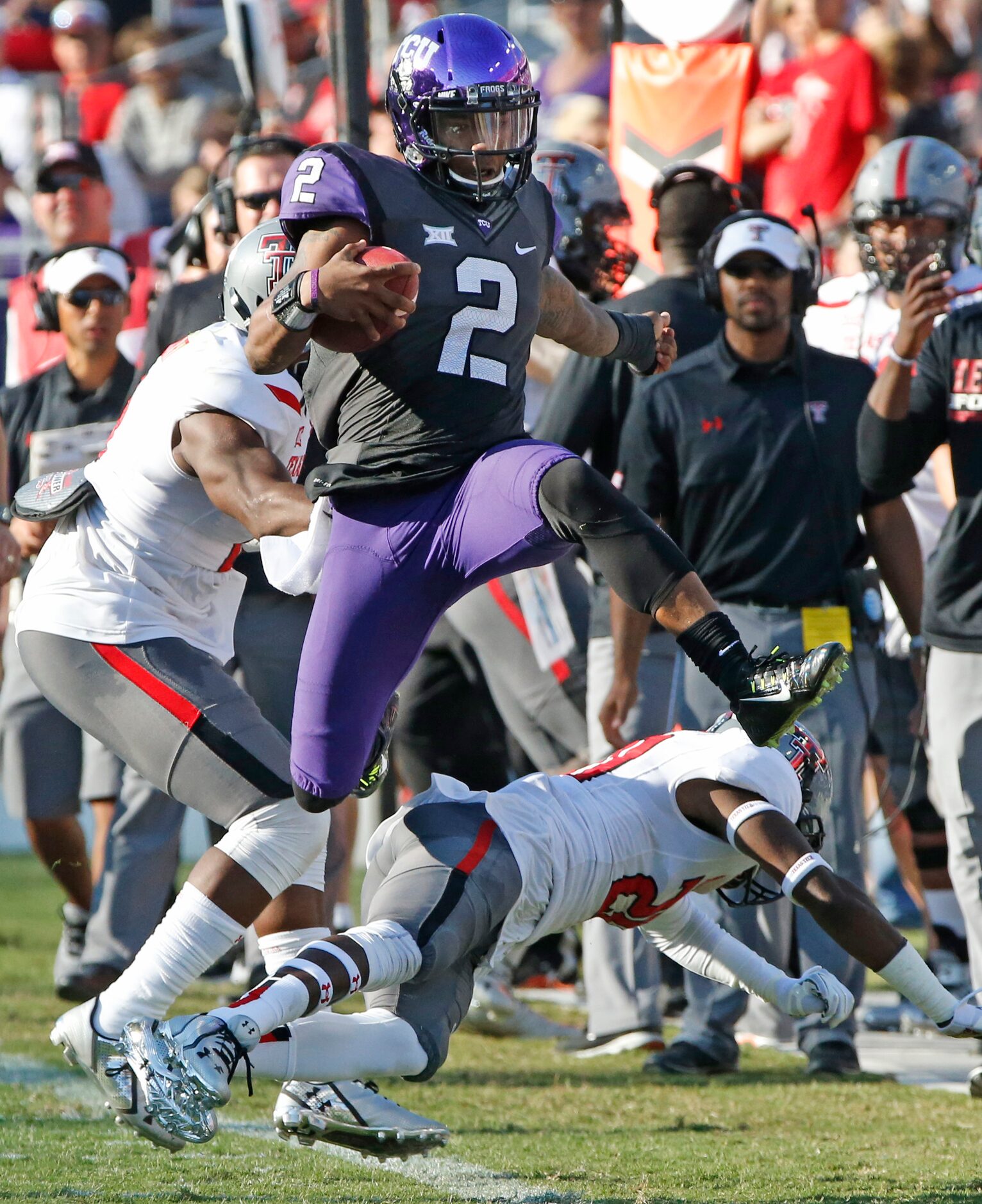 TCU quarterback Trevone Boykin (2) hurdles Texas Tech defensive back Tevin Madison (20) on a...