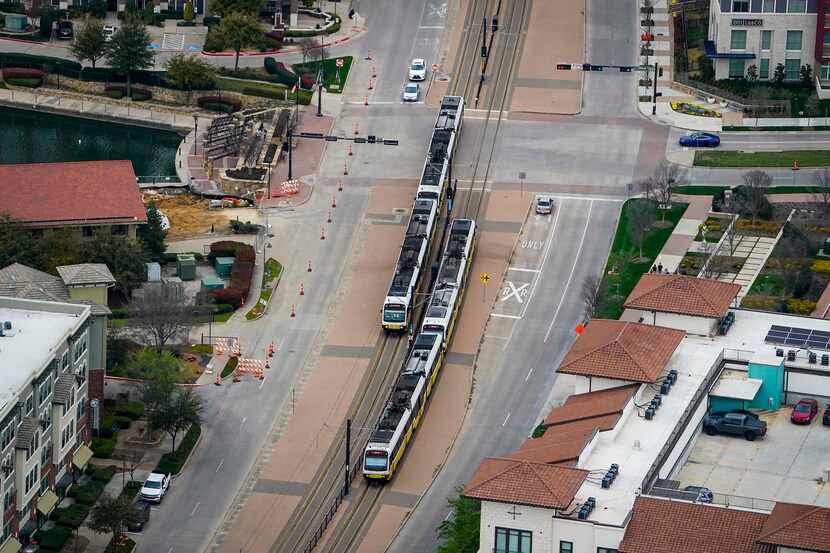 Aerial view of DART rail trains passing near Urban Center station in Las Colinas on...