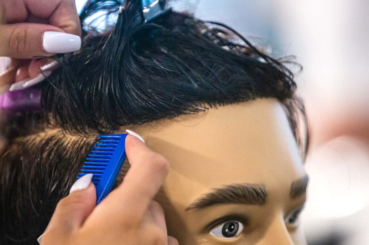 Student Megan Yruegas practices sectioning hair on a mannequin at Blade Craft Barber Academy.