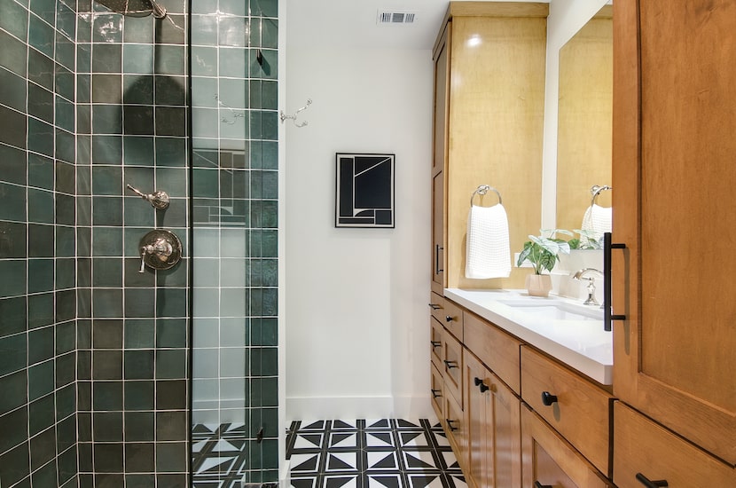 Bathroom with black-and-white floors, green tile in the shower and natural wood vanity with...