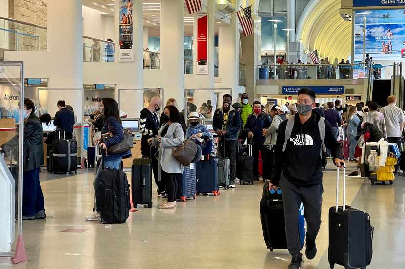 Passengers wait in line at the American Airlines check-in counters at the Los Angeles...