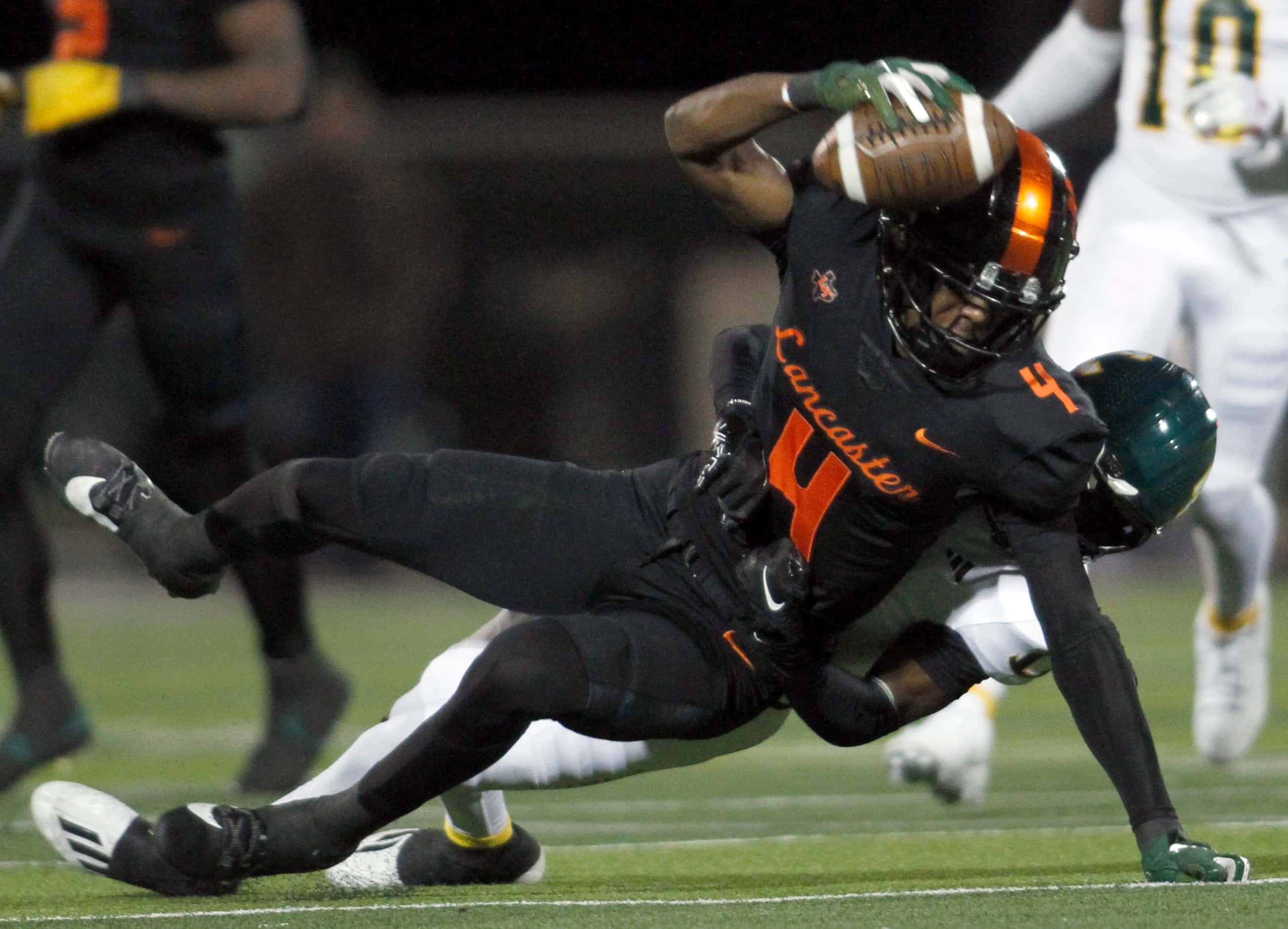 Lancaster receiver Emmanuel Choice (4) traps the ball against his helmet as he is tackled by...