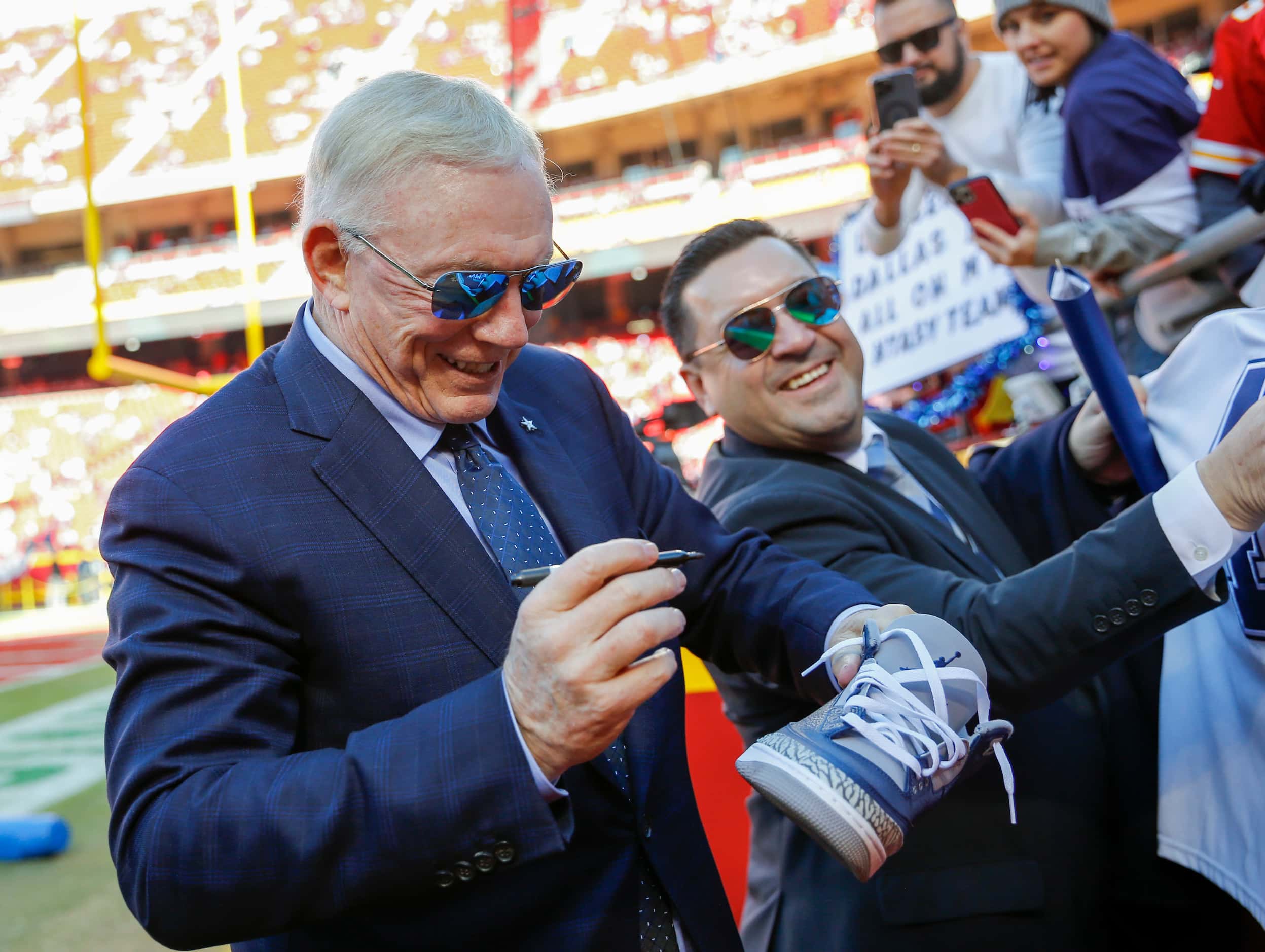 Dallas Cowboys owner Jerry Jones autographs a shoe for a fan before an NFL football game...