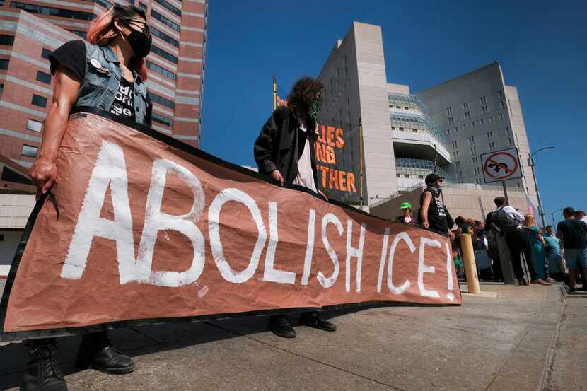 Protesters display a sign that reads "Abolish ICE" during a rally in front of the...