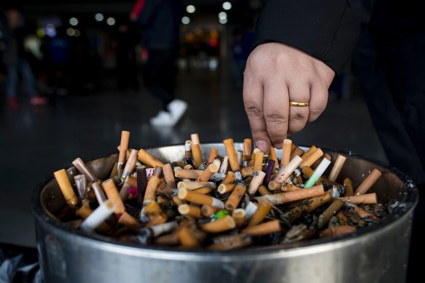 In this photo taken on February 28, 2017, a man grinds out his cigarette in an ashtray at a...