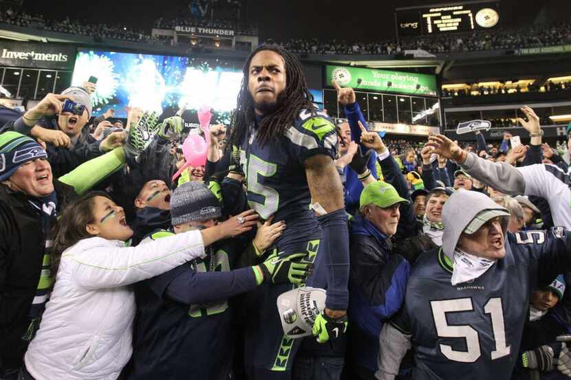 Seattle cornerback Richard Sherman climbs into the crowd to celebrate at the end of the NFC...
