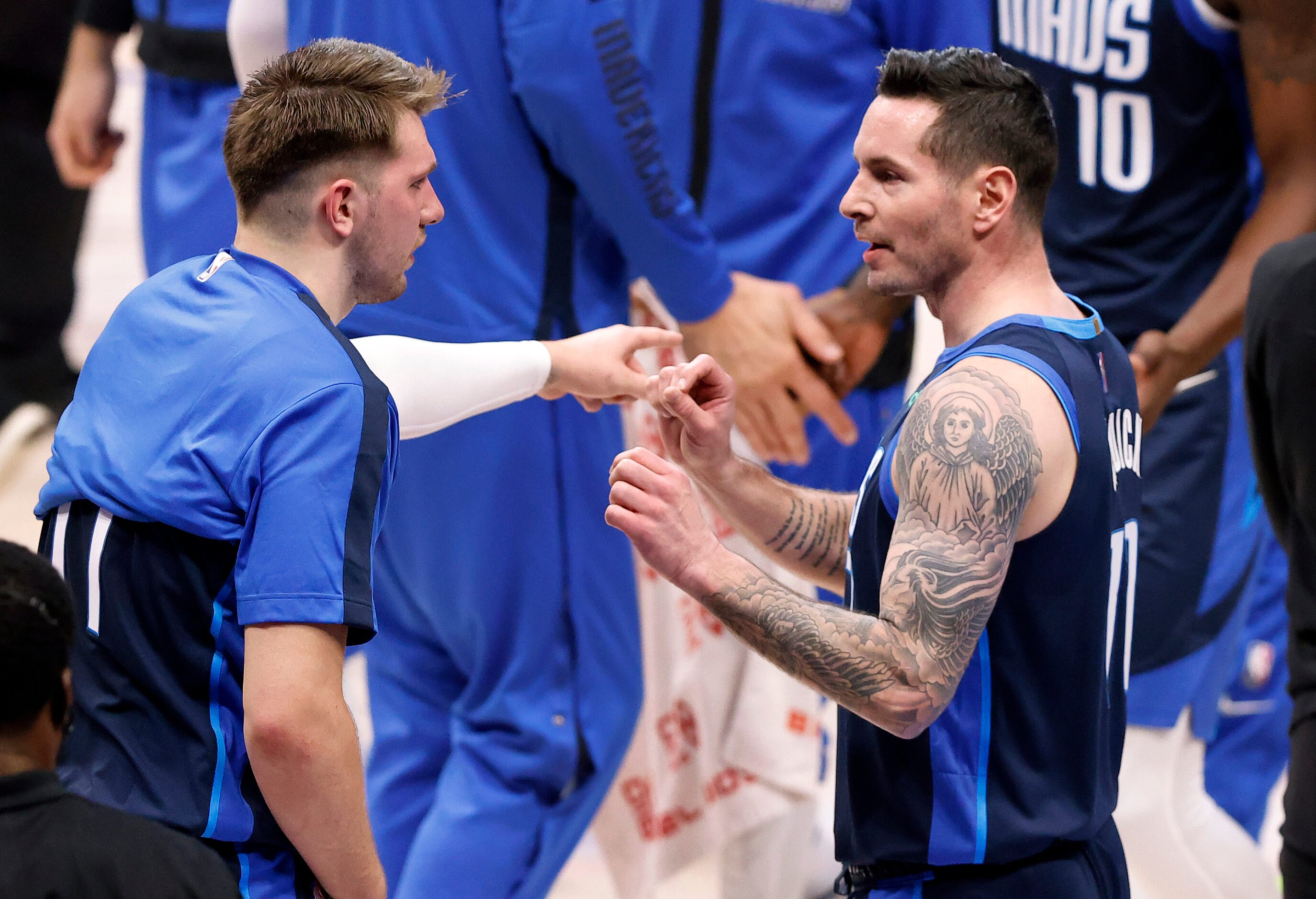 Dallas Mavericks guard JJ Redick (right) receives some pointers from teammate Luka Doncic...