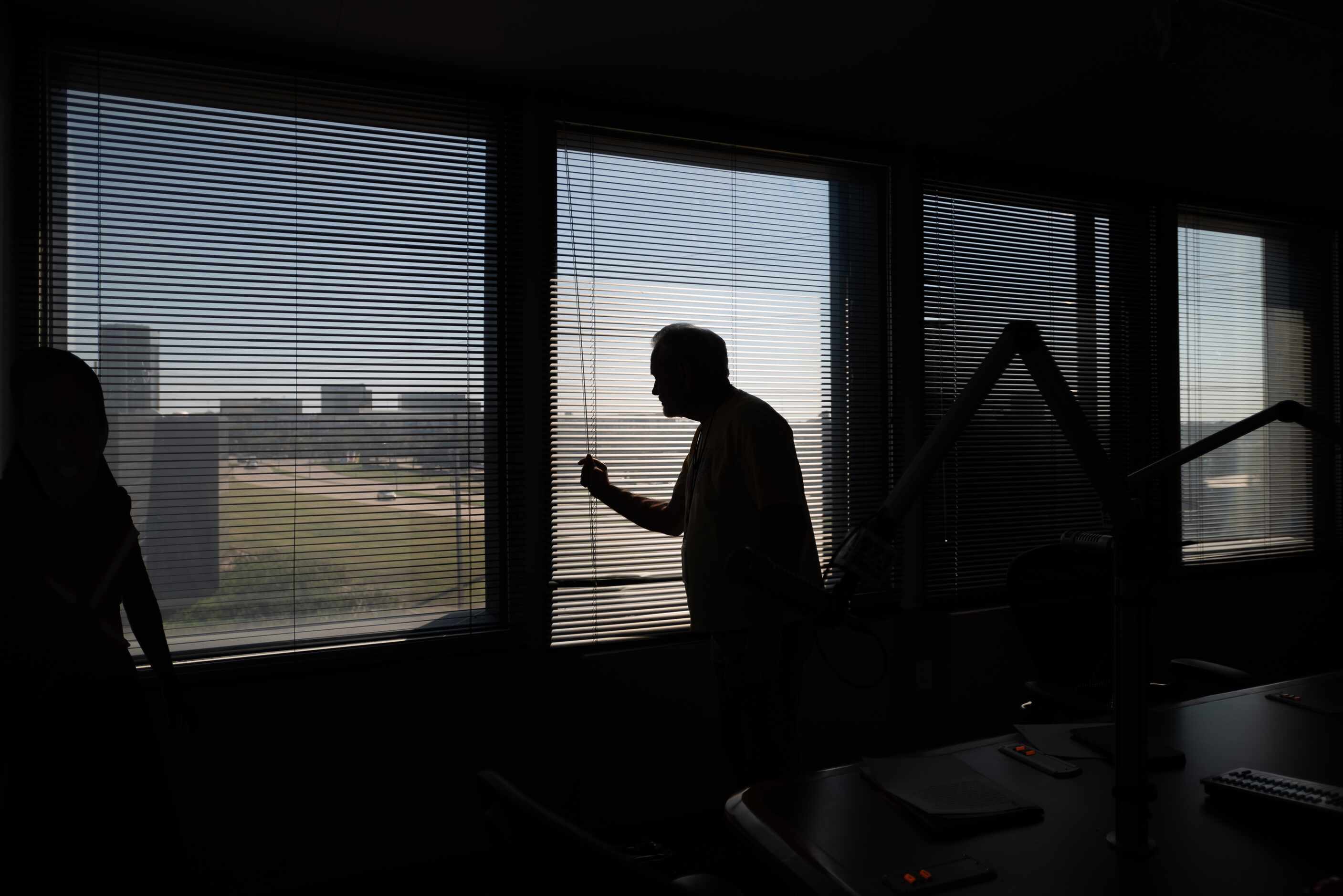 Mike Rhyner closes a set of window blinds as he prepares to host his show, The Downbeat.