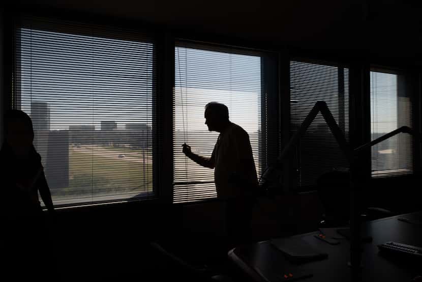 Radio legend Mike Rhyner closes a set of window blinds as he prepares to host the sports...