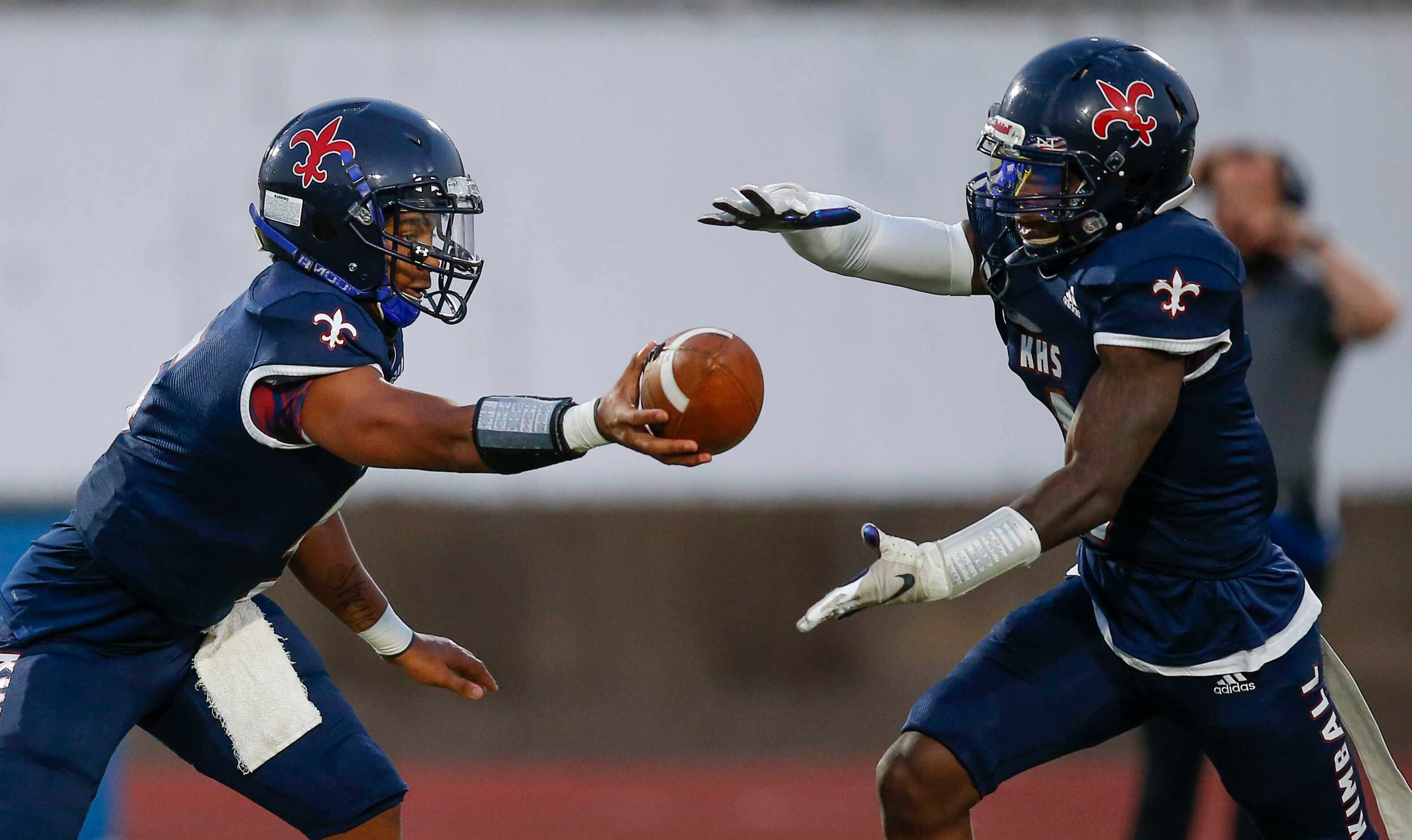 Kimball sophomore quarterback Jacarion Sauls, left, hands the ball off to senior running...