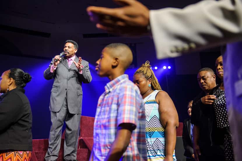 Pastor Dr. Tony Evans talks to the congregation as his ministers lead a group to a side room...
