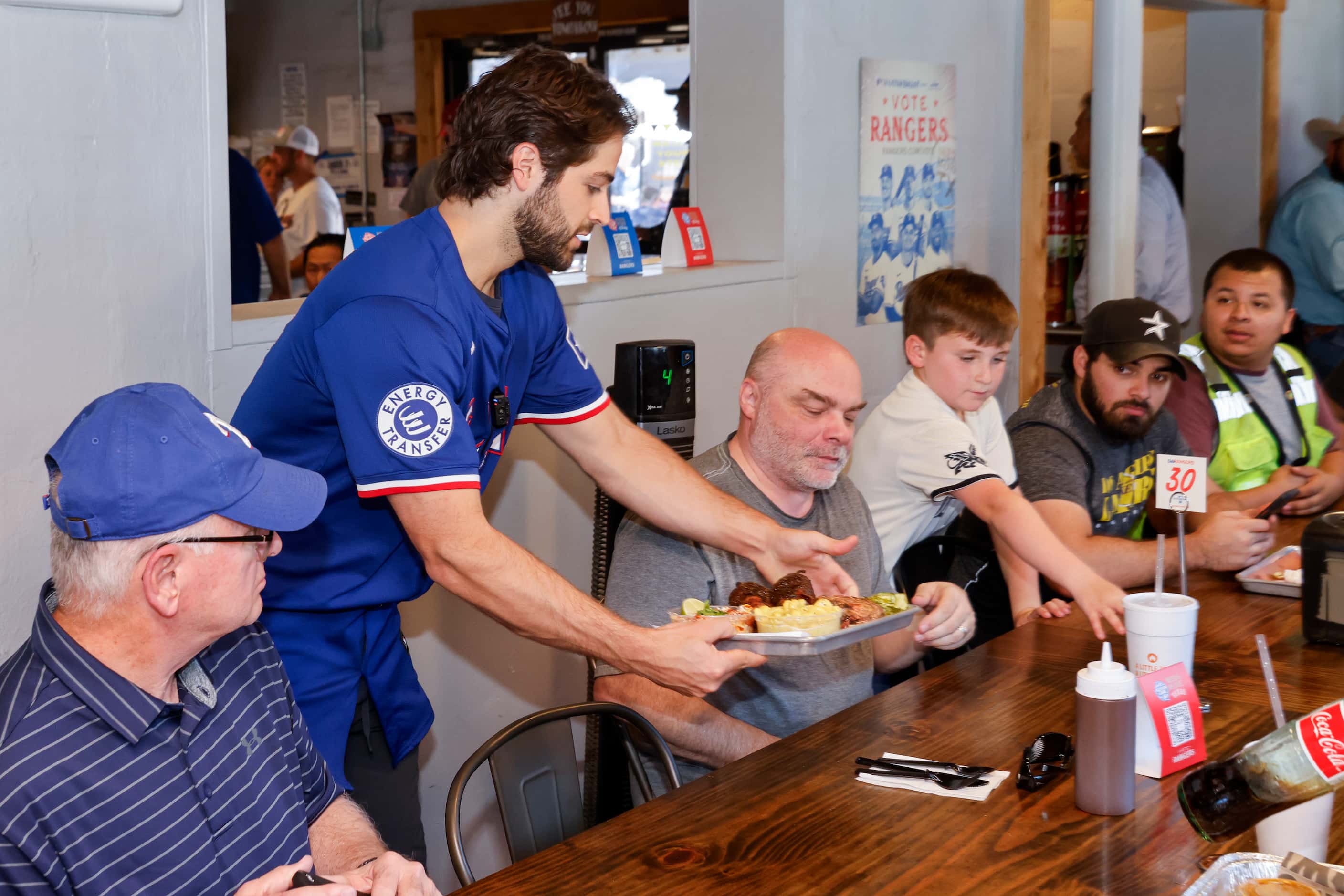 Texas Rangers third baseman Josh Smith delivers a tray of barbecue to customers at Hurtado...