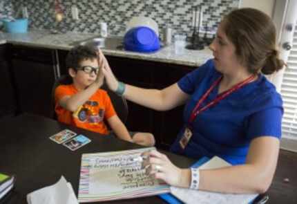  Jacob Casablanca (left) high-fives speech therapist Elizabeth Price during their session...