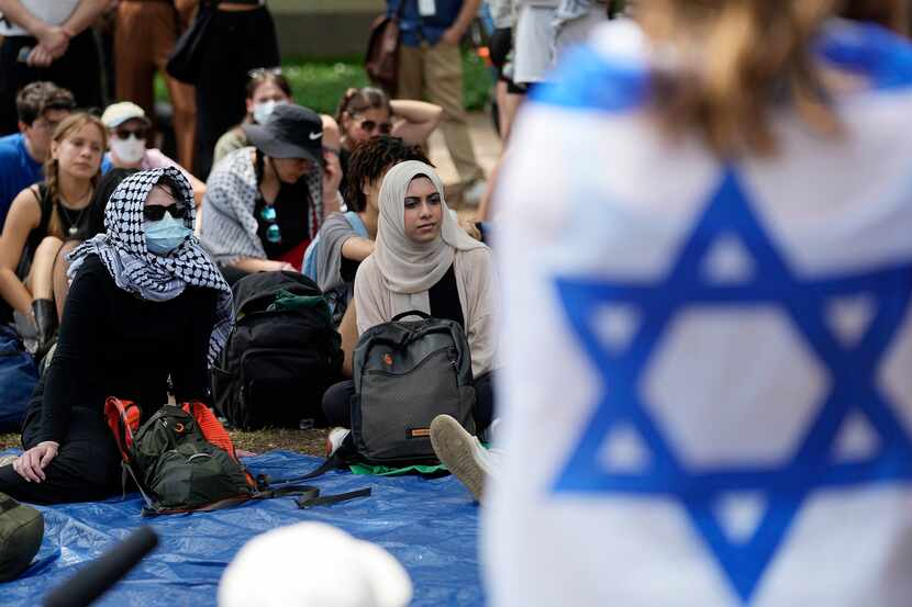 A student wrapped in an Israeli flag listens to Pro-Palestinian protesters gathered on...