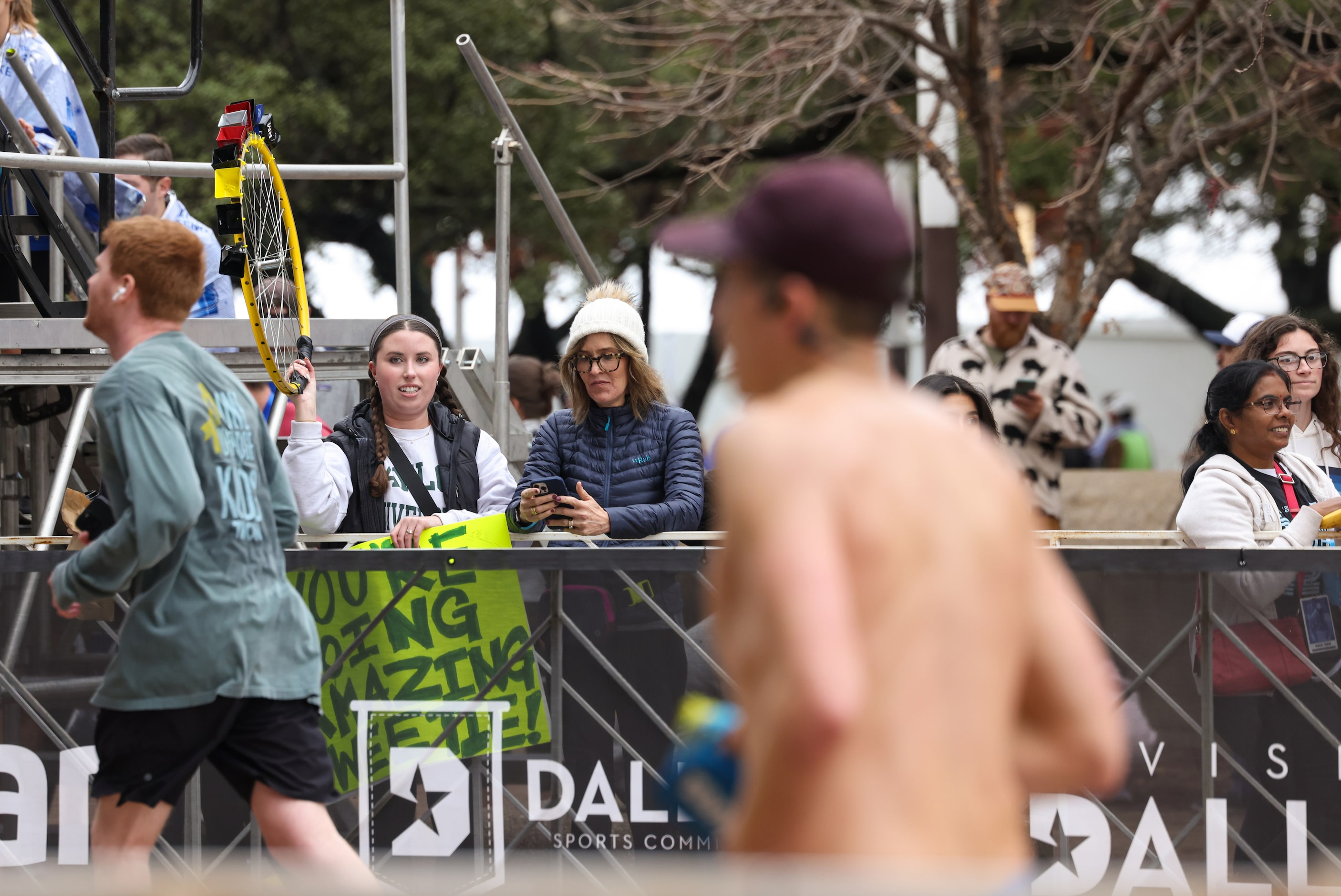 Clara McIntosh (left) shakes a bicycle wheel outfitted with bells for runners as they...