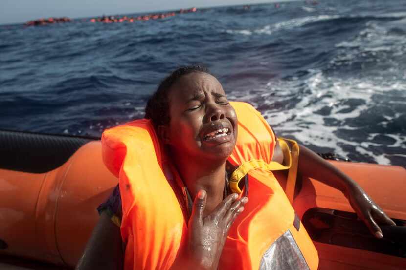 A woman cries after losing her baby in the water as she sits in a rescue boat from the...