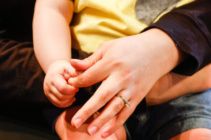 Alex Ibarra holds the finger of his mother, Brenda Raymundo.