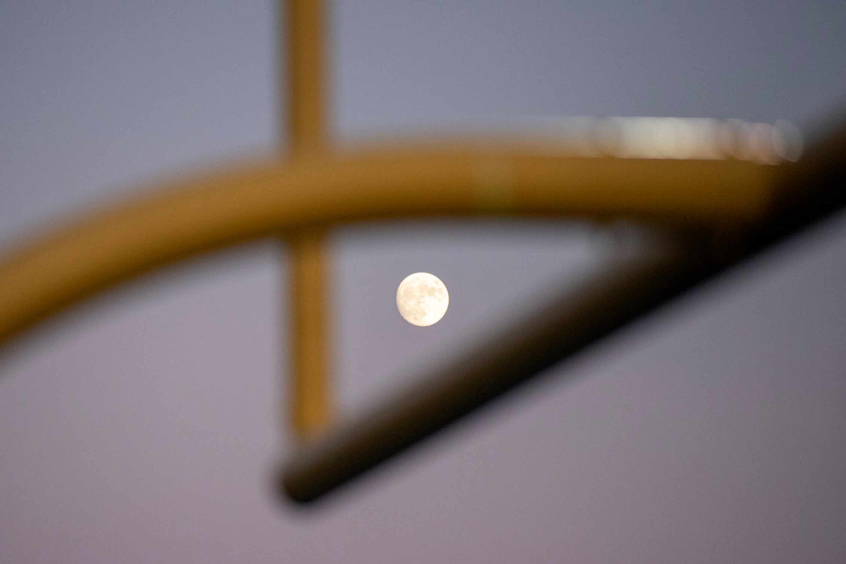 The rising moon is seen through the north goal post of Postell Stadium during the first half...