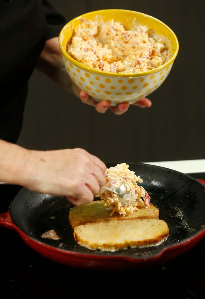 Pimiento cheese is put on grilling bread for grilled cheese sandwiches
