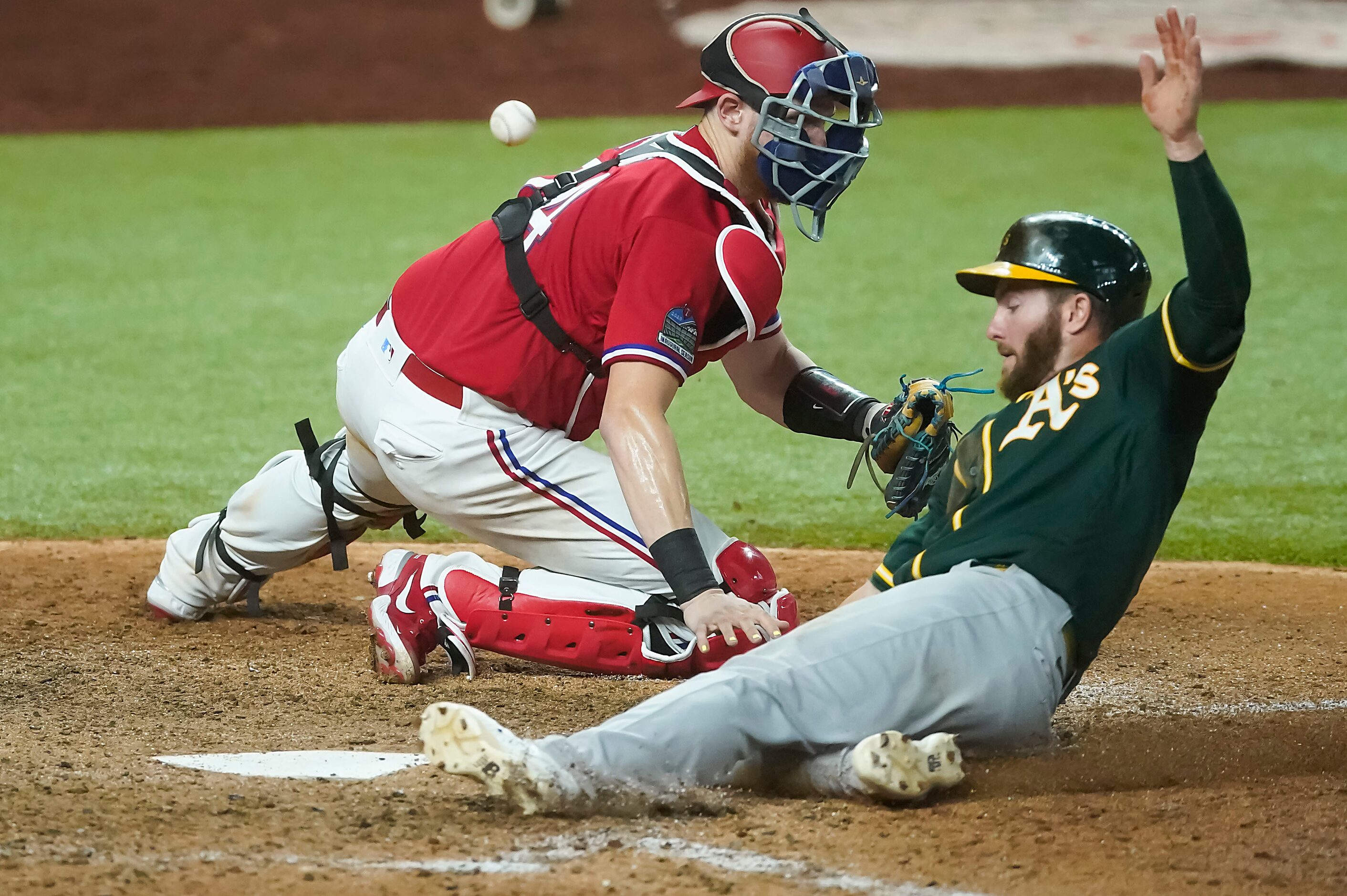 Oakland Athletics left fielder Robbie Grossman scores as the throw gets away from Texas...