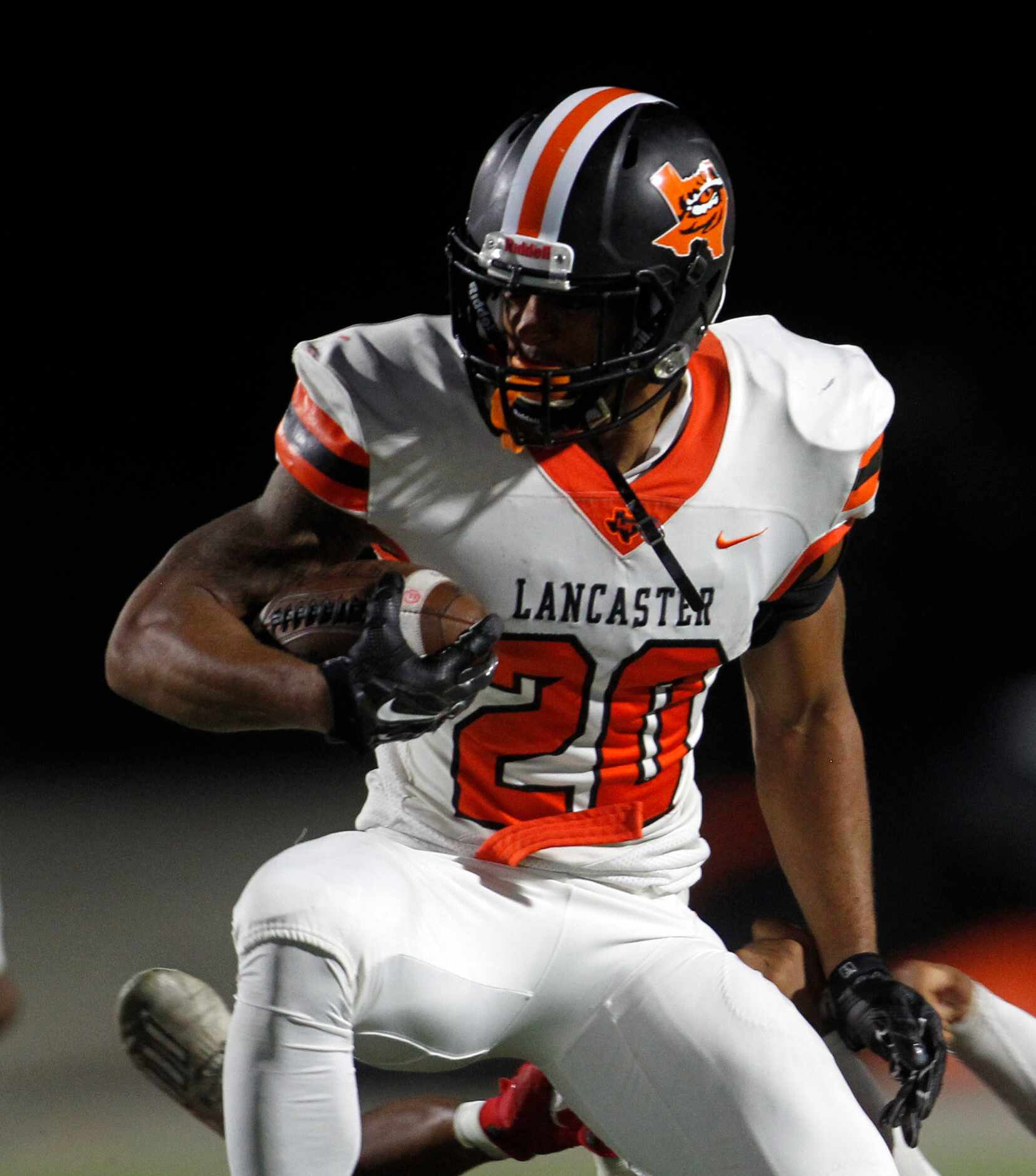 Lancaster running back Isaiah Broadway (20) looks for running room as he rushes into the...