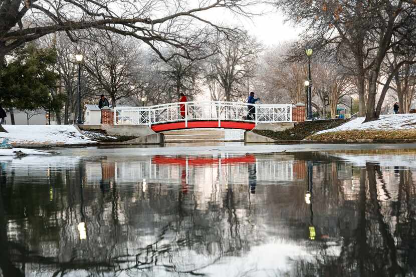 People walk over a bridge on Friday, Feb. 4, 2022 in Plano, TX, a day after a winter storm...