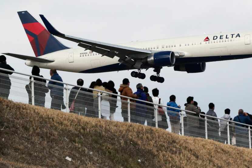  In this March 14, 2015, file photo, people watch a landing Delta Air Lines jet approach the...