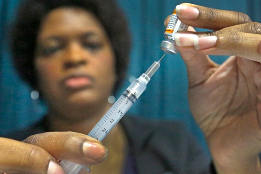 A health care provider prepares to administer an immunization Aug. 3 at the Dallas Mayor's...