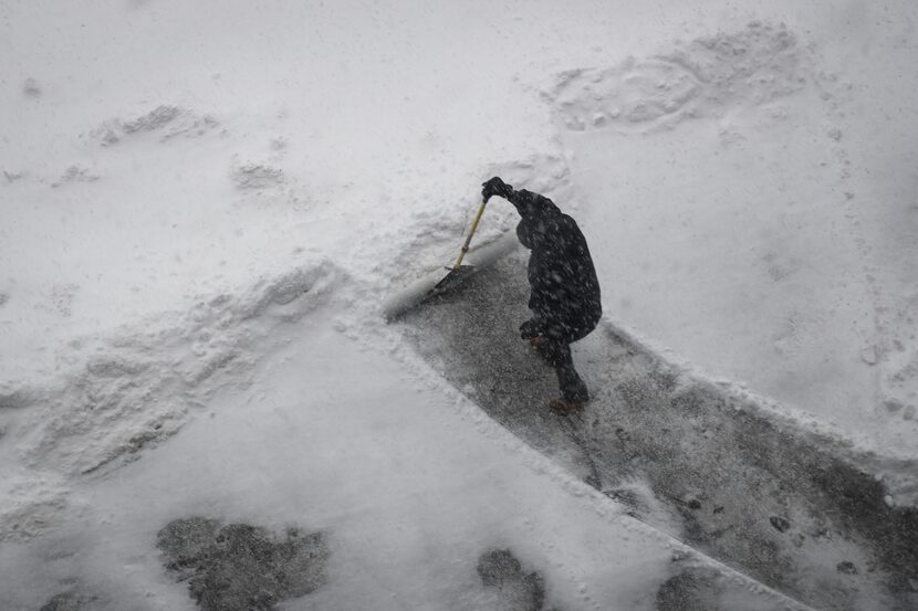 NEW YORK, NY:  A worker shoves a sidewalk in Brooklyn Bridge Park during a winter storm,...