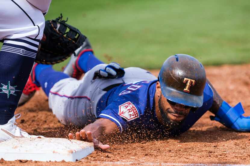 Texas Rangers outfielder Delino DeShields dives back in to first base to avoid a pickoff...