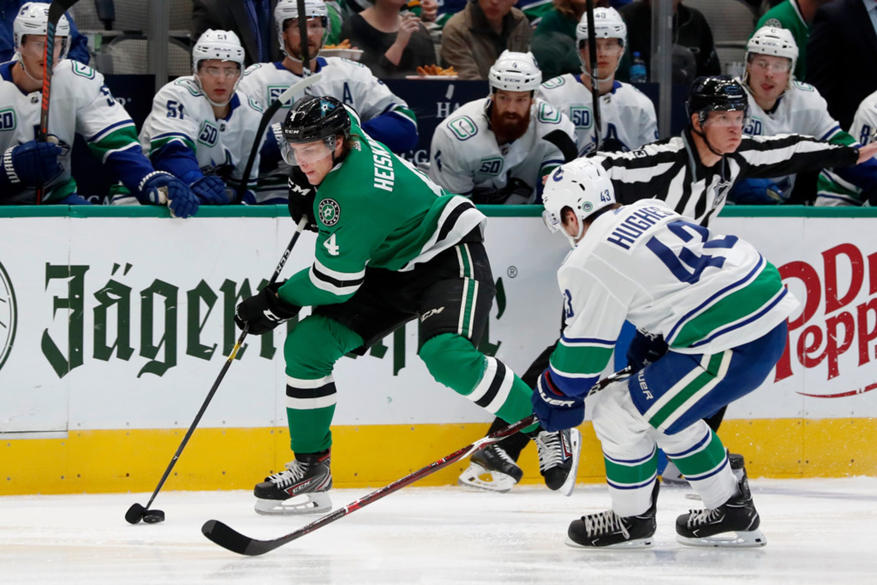 Dallas Stars defenseman Miro Heiskanen (4) controls the puck in front of Vancouver Canucks...