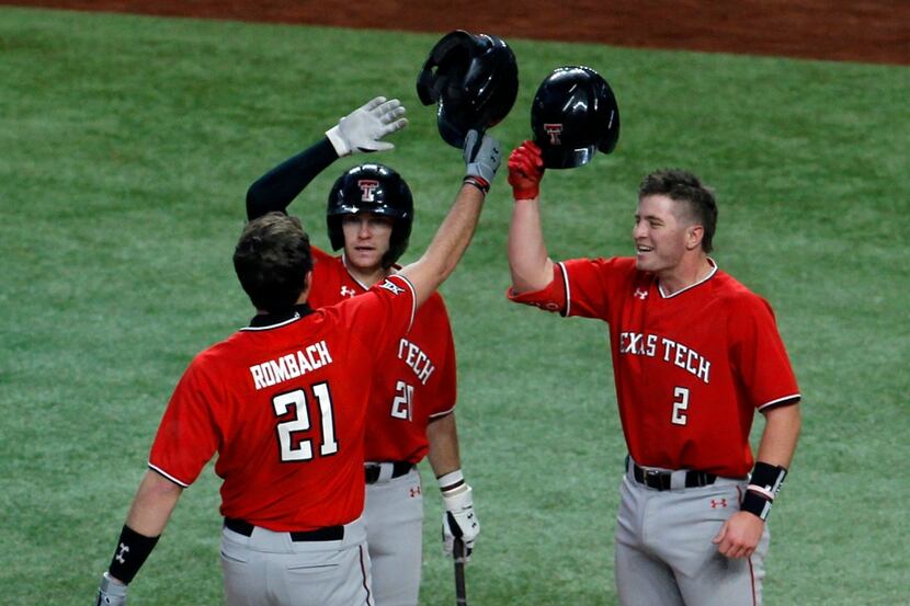 Texas Tech freshman infielder Nate Rombach (21) is greeted at home plate by teammates Max...