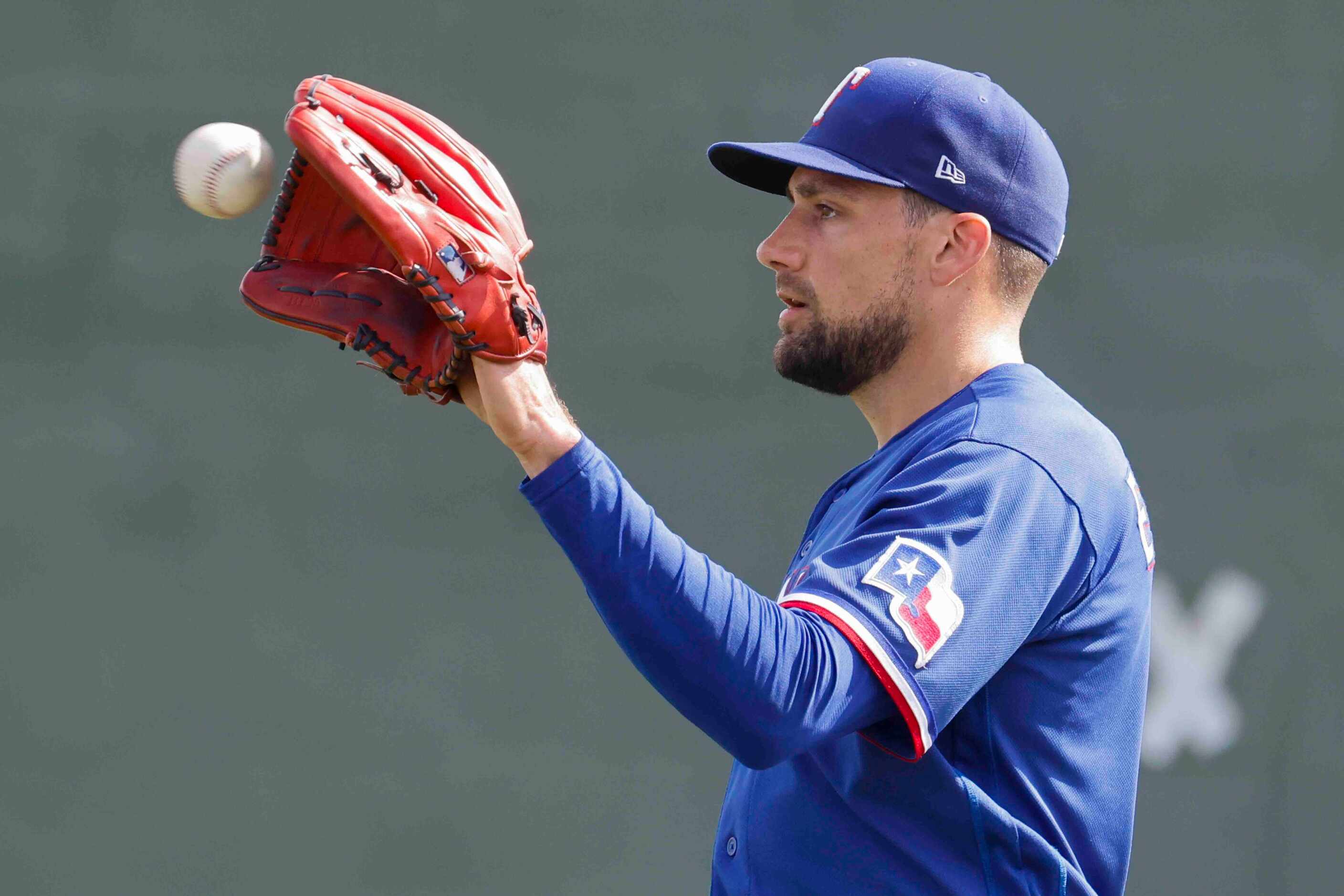 Texas Rangers pitcher Nathan Eovaldi catches a ball from a catcher during a spring training...