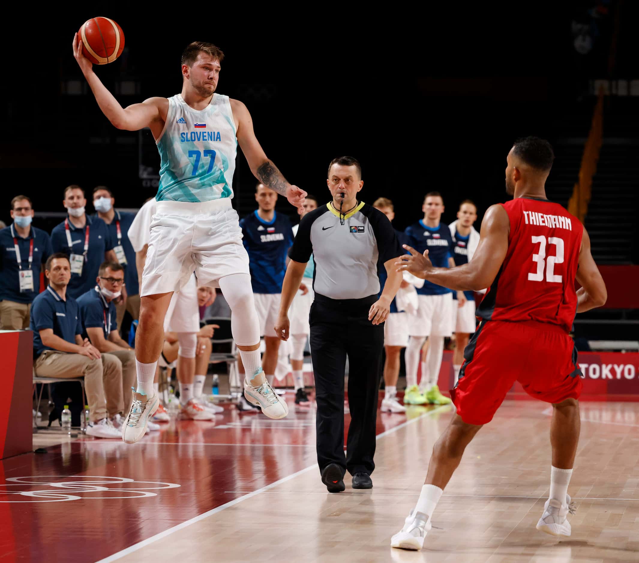 Slovenia’s Luka Doncic (77) saves a ball before going out of bounds in front of Germany’s...