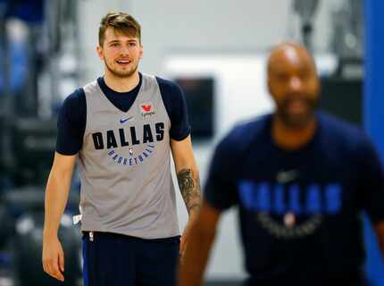 Mavericks rookie Luka Doncic (77) watches as assistant coach Jamahl Mosley takes a shot from...