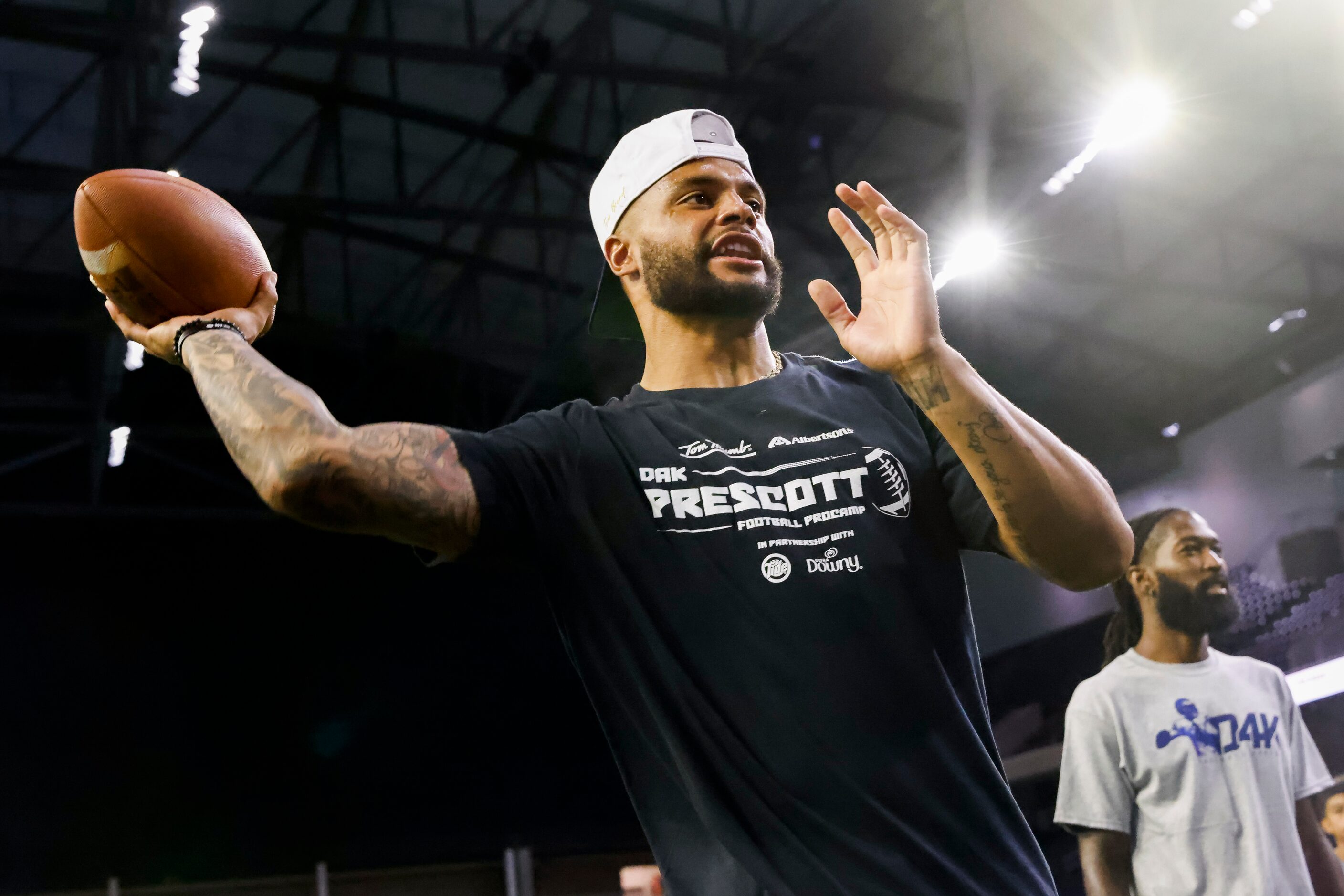 Cowboys quarterback Dak Prescott throws the ball while running drills with students during...