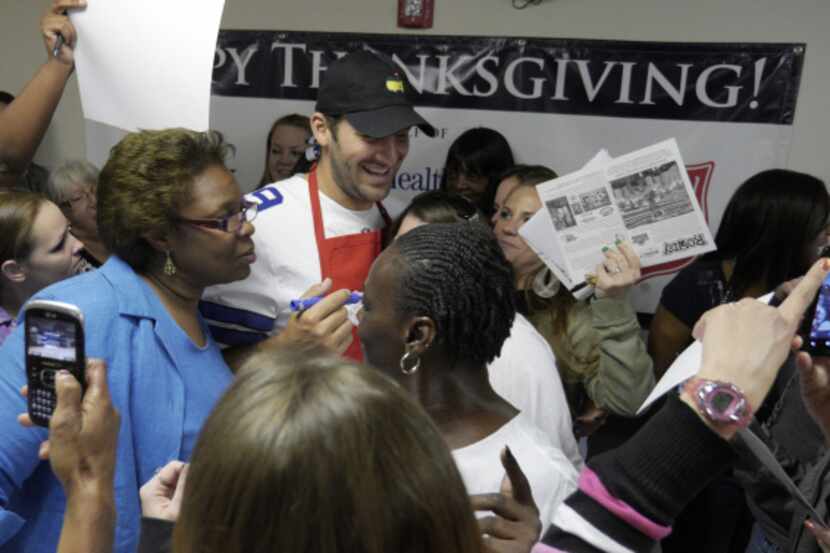 Dallas Cowboys quarterback Tony Romo is surrounded by female residents of The Salvation Army...