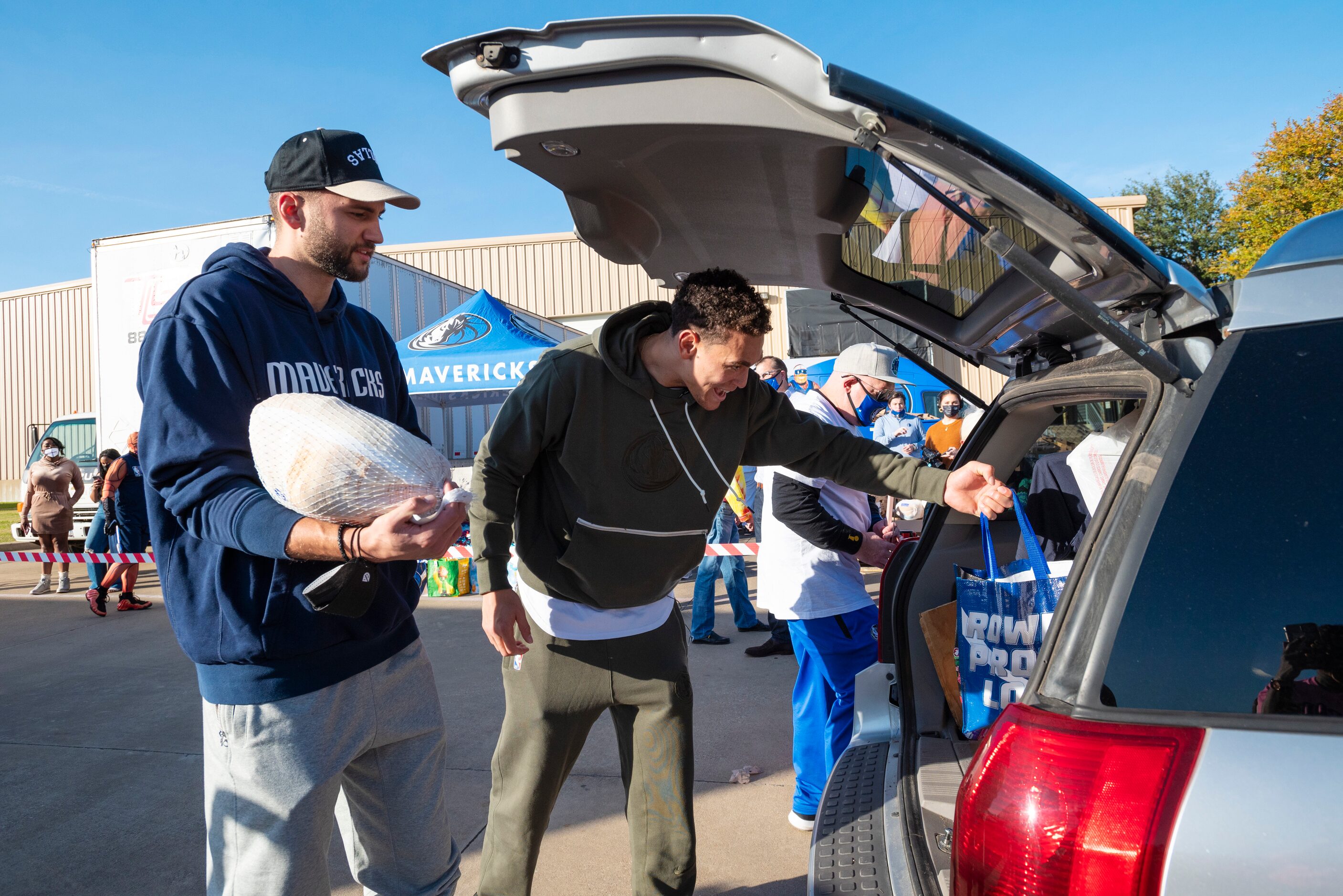 Dallas Mavericks players Maxi Kleber, left, and Dwight Powell, load a frozen turkey and...