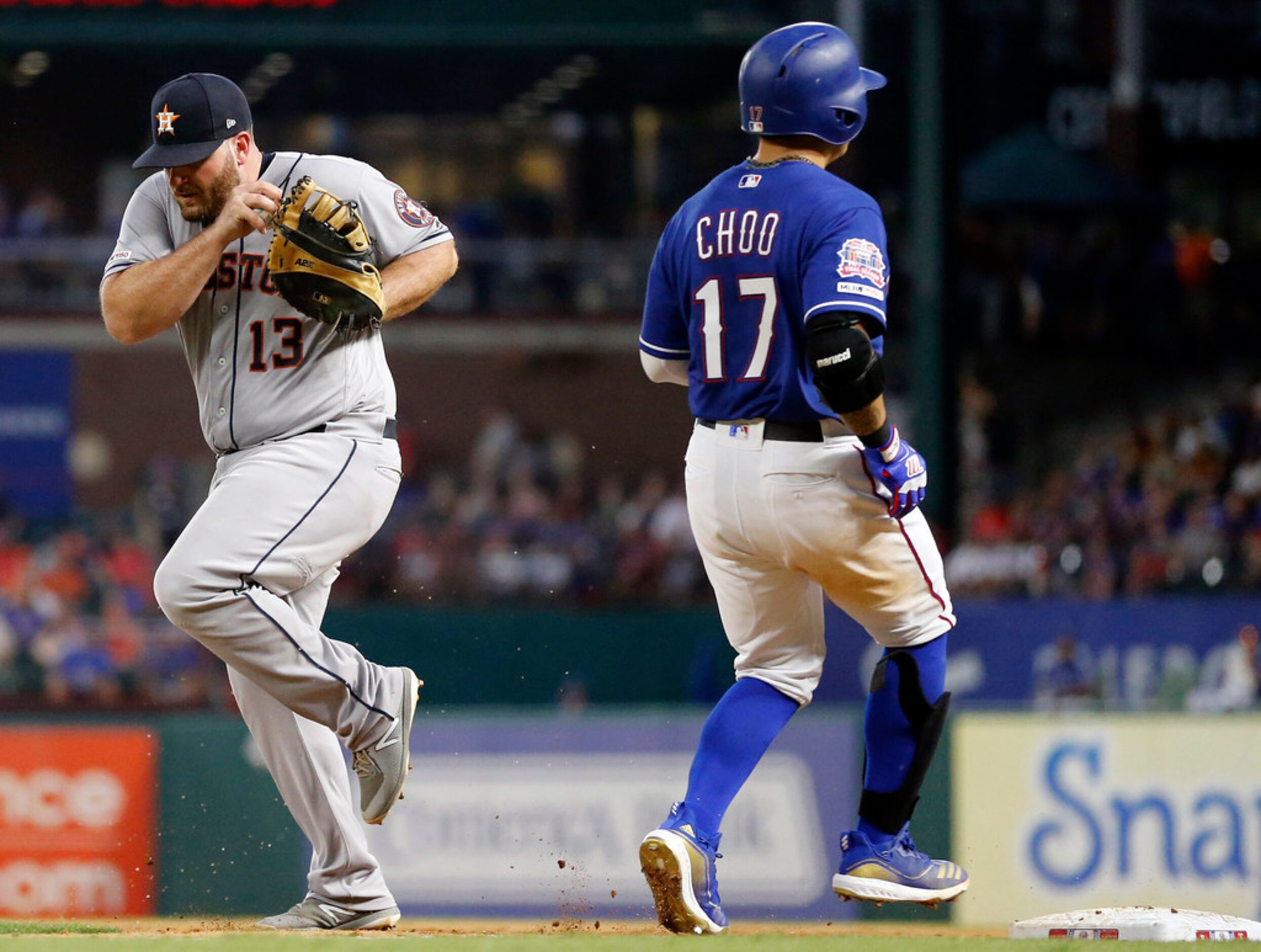 Houston Astros first baseman Tyler White (13) tip-toes past Texas Rangers batter Shin-Soo...