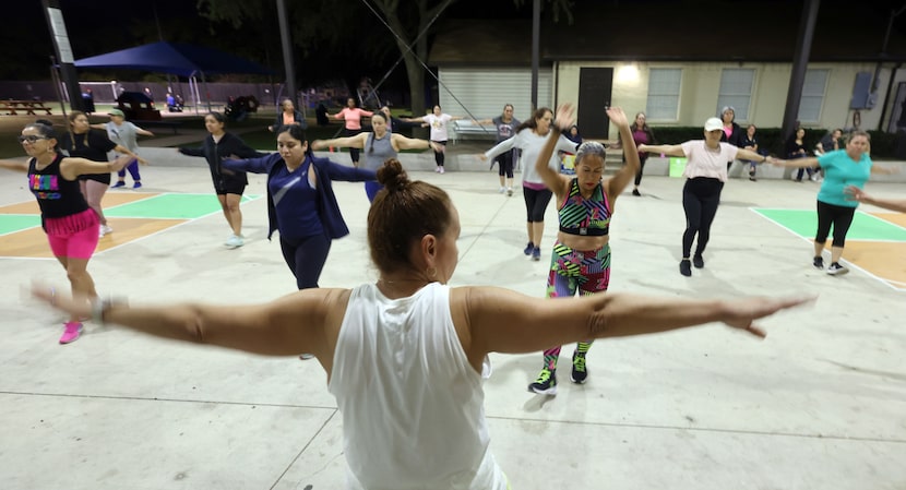 Zumba Instructor Angie DelCampo, foreground, guides class participants through a series of...