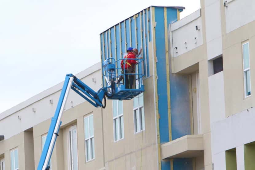  Workers place wooden beams on a building in the Standard apartment complex located a block...