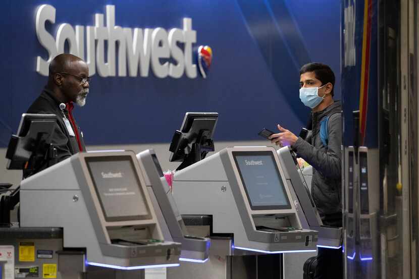A Southwest Airlines employees helps a passenger wearing a facial mask at LaGuardia Airport,...