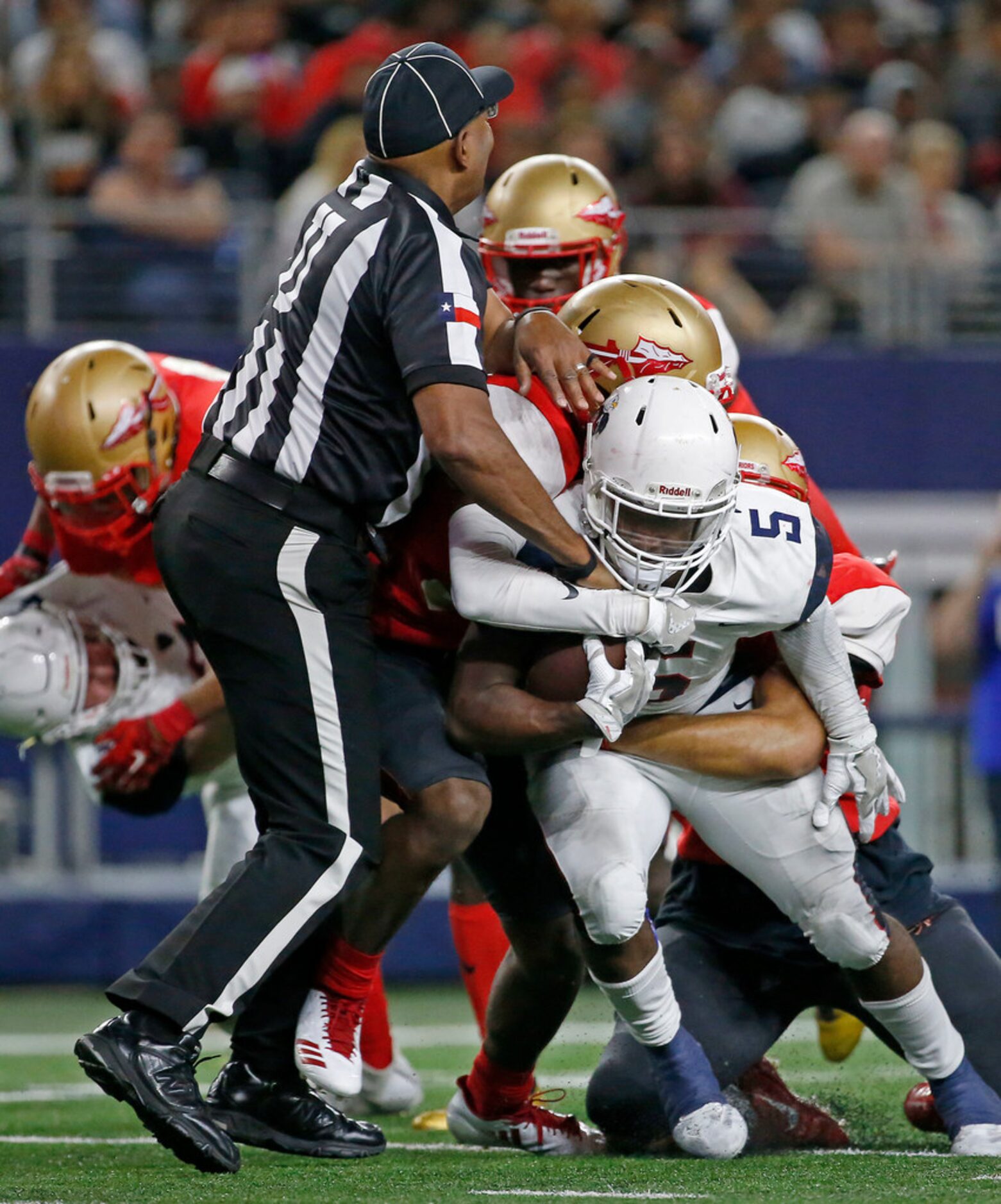 An umpire is hit by players as Allen's Brock Sturges (5) is tackled by South Grand Prairie's...