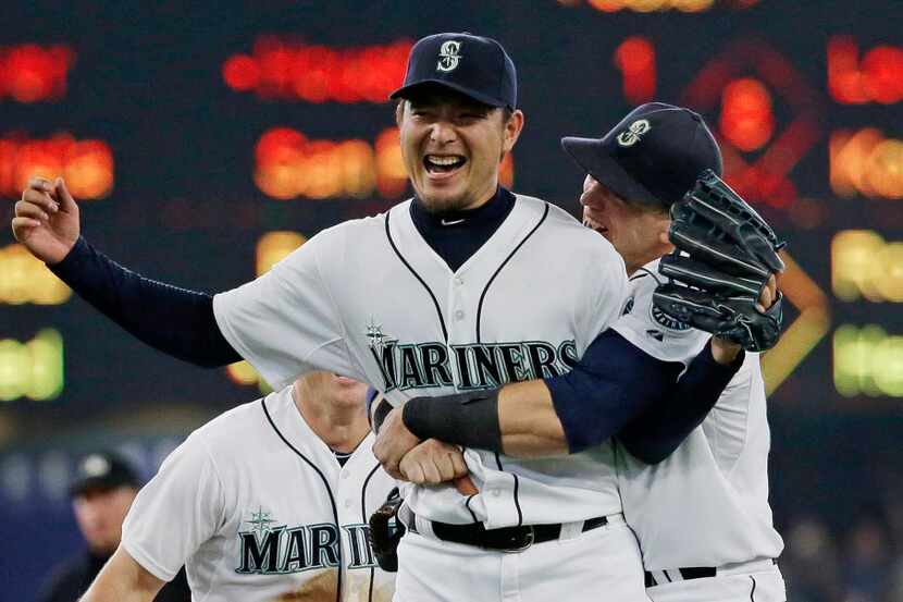 Seattle Mariners starting pitcher Hisashi Iwakuma is hugged by first baseman Logan Morrison,...