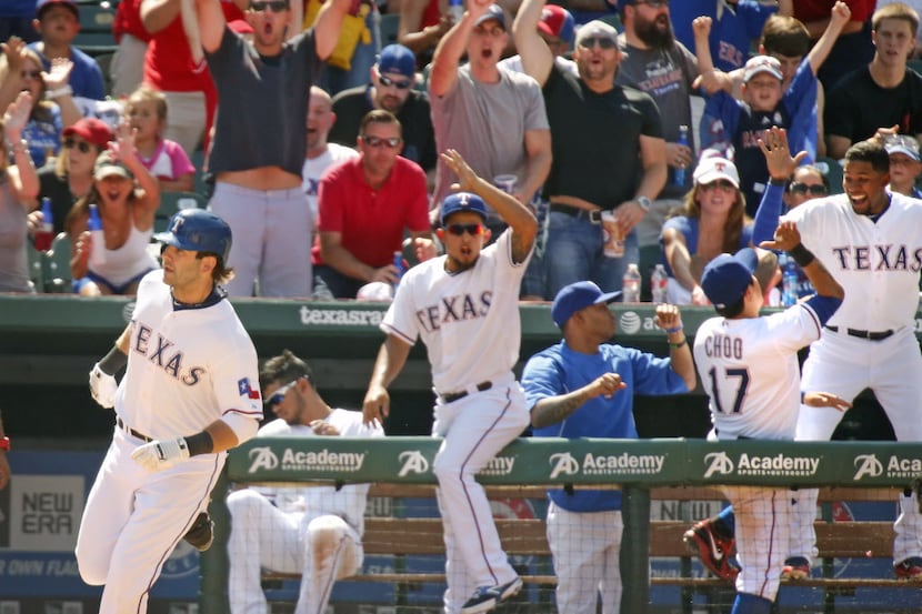 The Rangers dugout and fans celebrate as first baseman Mitch Moreland rounds first after...