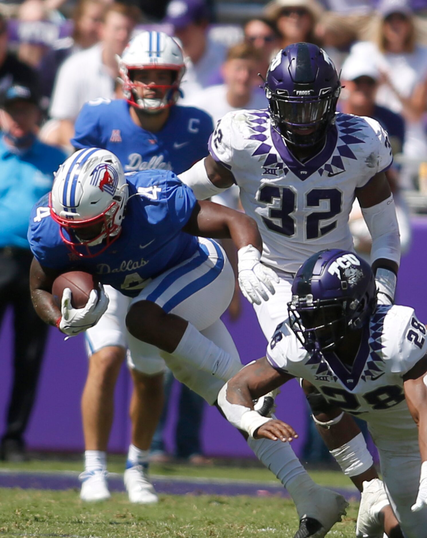 SMU running back Trey Siggers (4) pulls away from TCU defenders Nook Bradford (28) and...