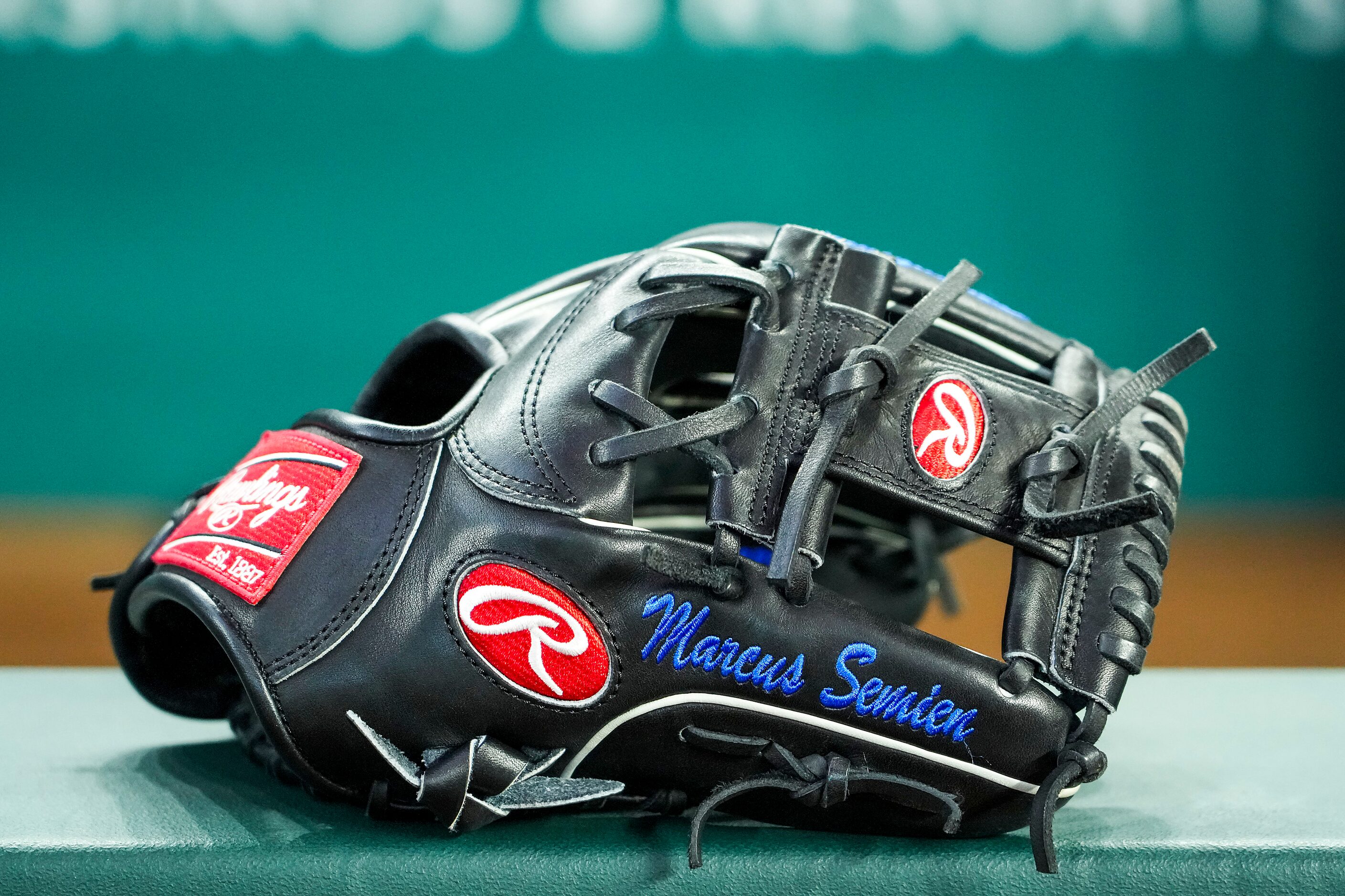 The mitt of Texas Rangers second baseman Marcus Semien rests on the dugout rail during...