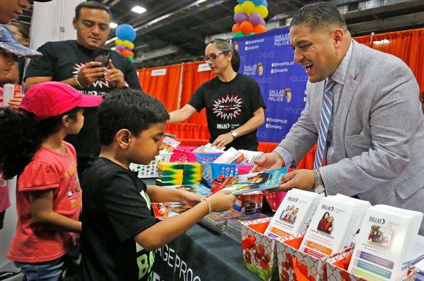 Dallas school board member Jaime Resendez hands out items to parents and students at the...