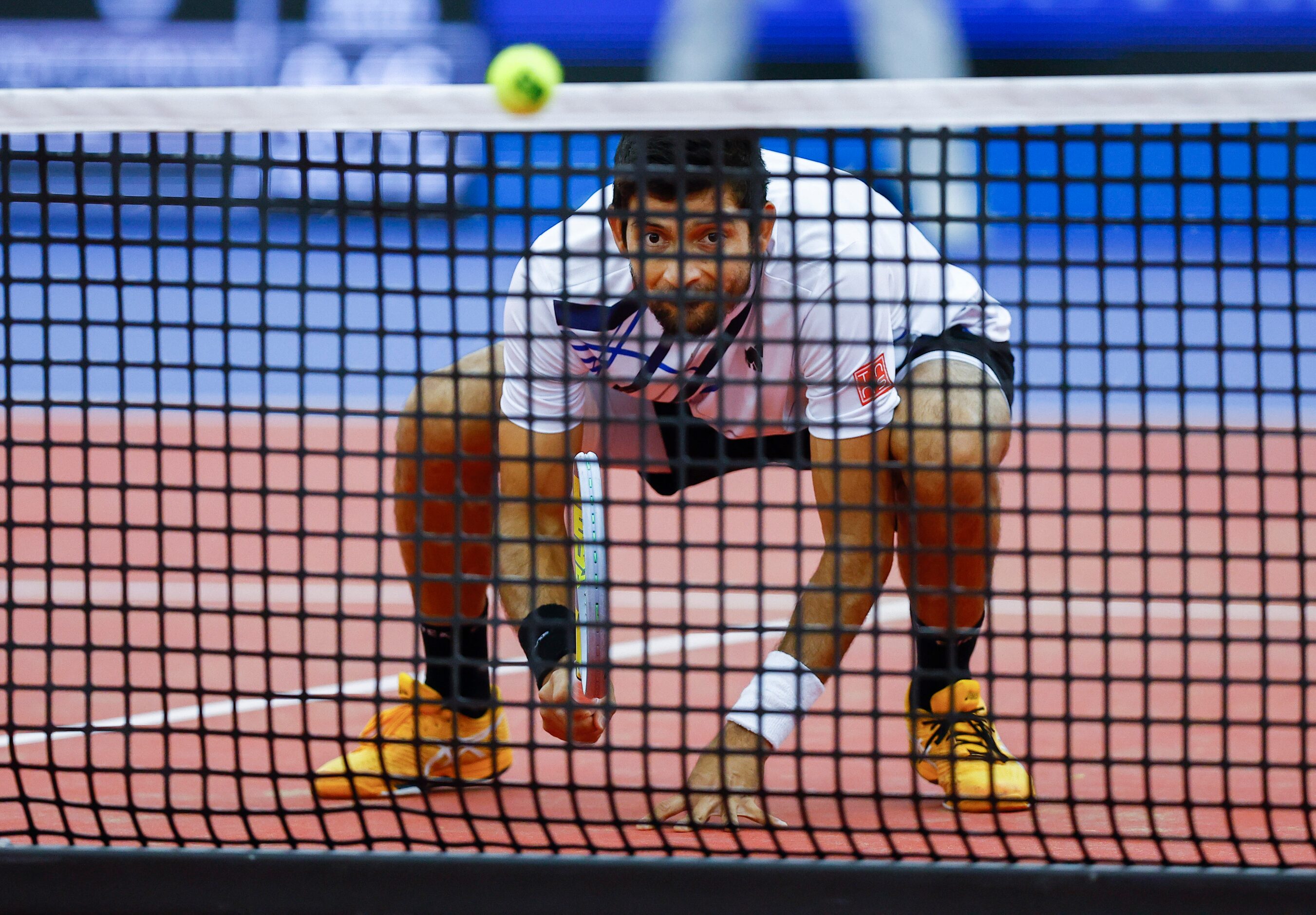 Marcelo Arevalo kneels allowing his teammate Jean-Julien Rojer to serve the ball over him...