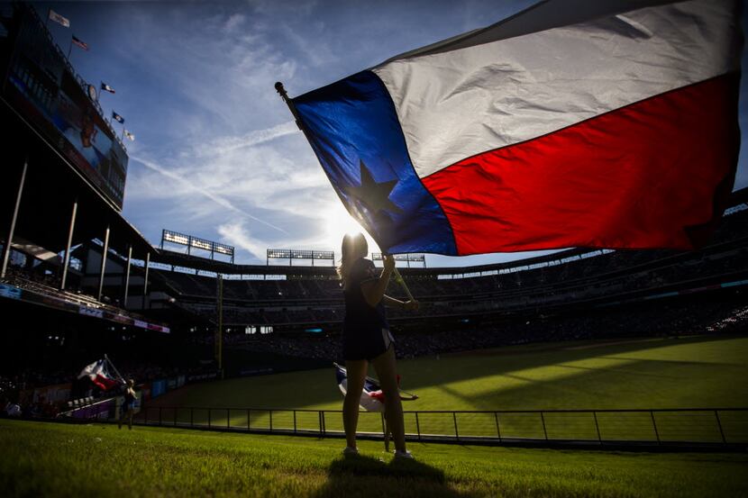 Texas Rangers Six Shooter Jaime Thatcher waves a Texas flag in the outfield before their...